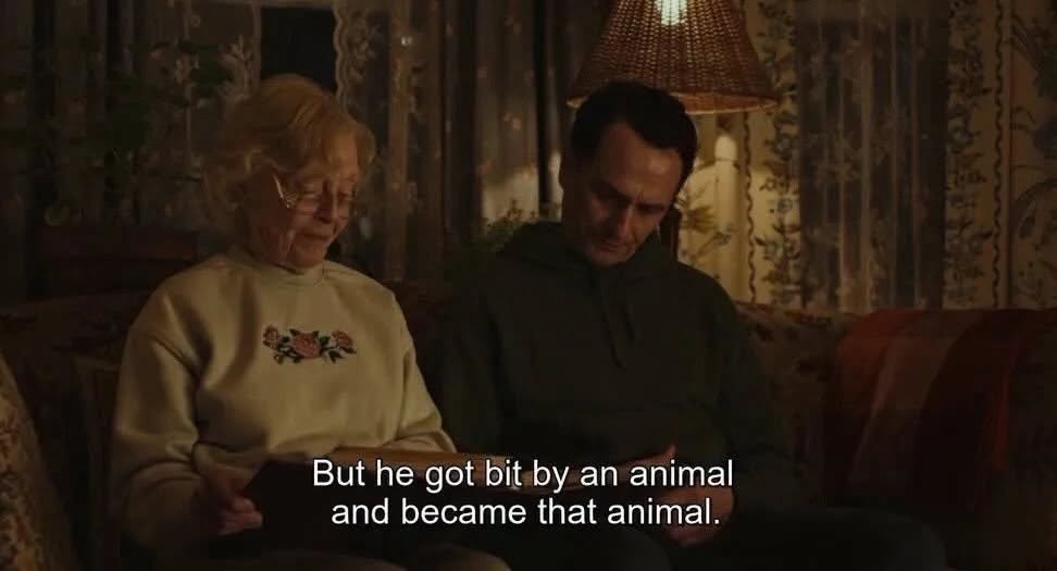 Still from Widow&rsquo;s Bay showing Ruth and Tom on a couch. The subtitle reads: "But he got bit by an animal and became that animal."